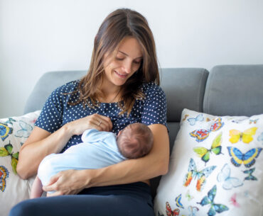 mom sitting on couch breastfeeding