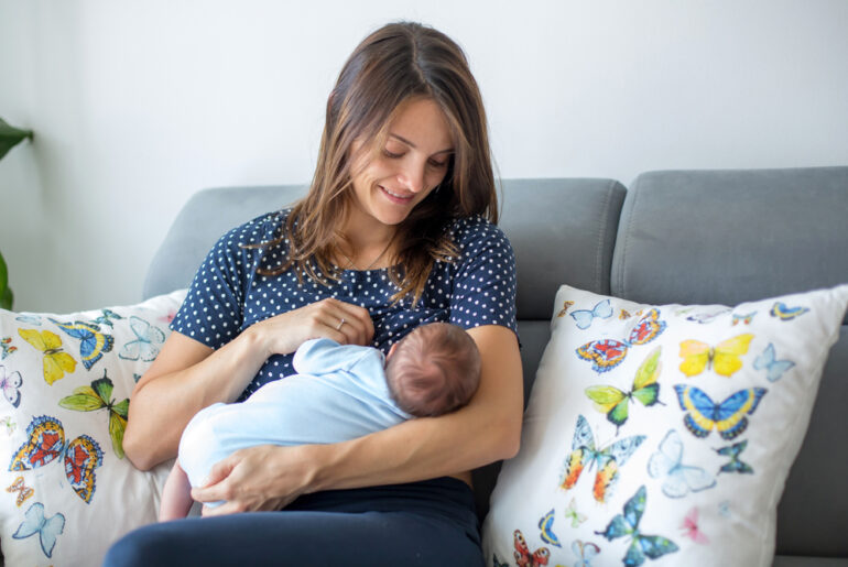 mom sitting on couch breastfeeding